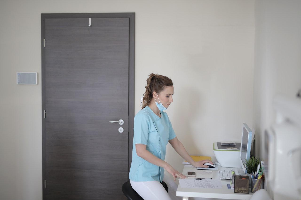 Woman in scrubs in front of a computer