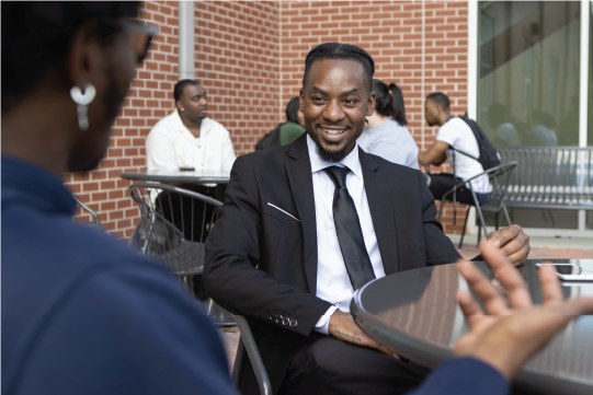 Student in a suit talking to another student