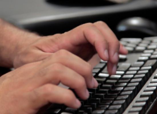 Hands typing on a laptop